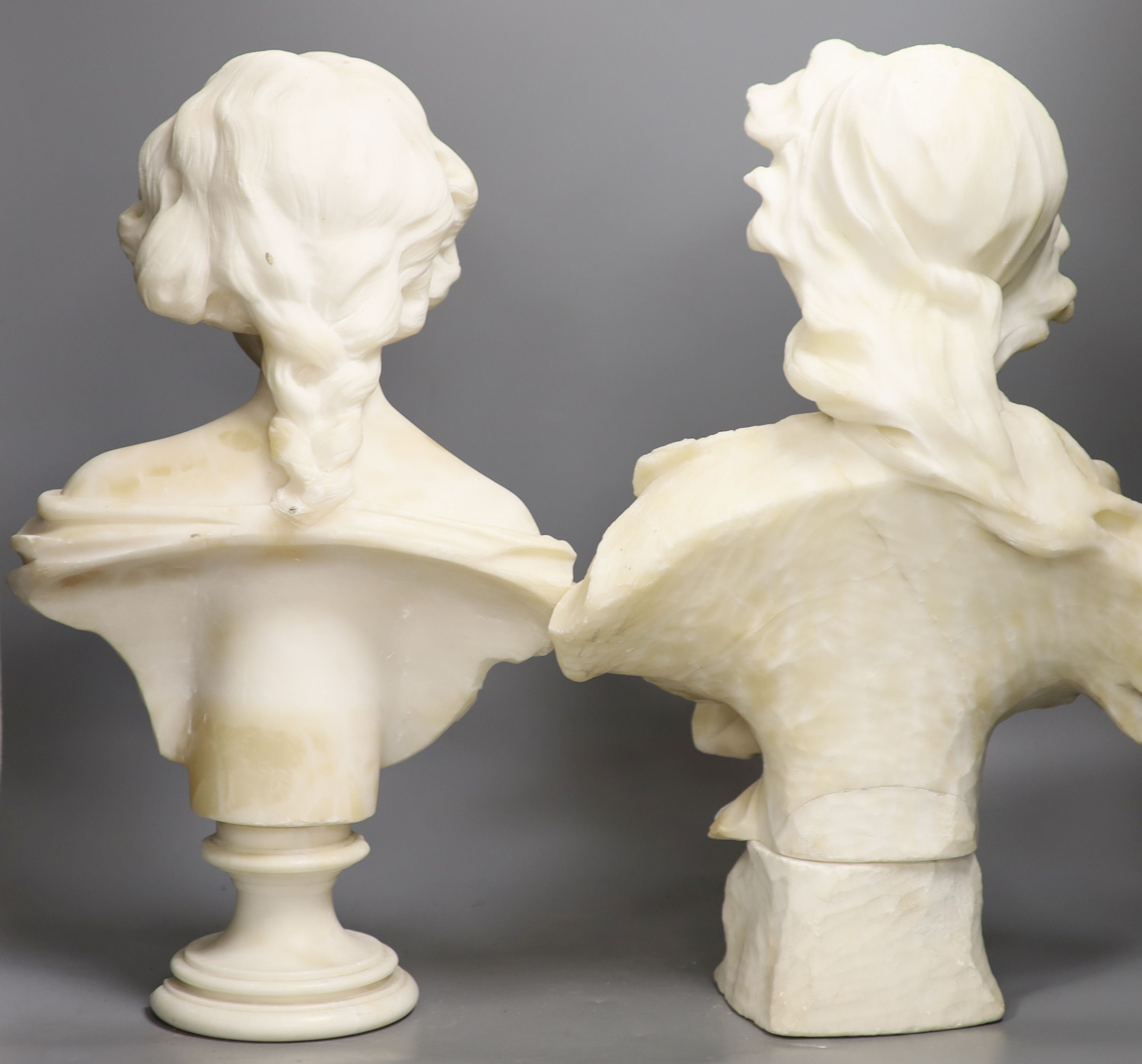 Two white alabaster busts of young women, raised on turned plinths 44cm